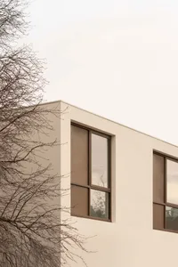 A white building with large windows on its side, surrounded by natural light, giving a sense of openness and brightness