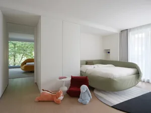 Cozy bedroom with a large bed, white headboard and footboard, a stuffed animal, and a chair in a well-lit space