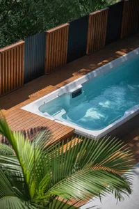 A serene pool area with a large empty pool surrounded by wooden decking and a nearby bench, perfect for relaxation and leisure