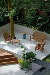 Well-lit outdoor patio with two wooden chairs and two benches on a concrete surface, inviting atmosphere