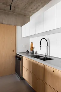 Warm kitchen with wooden cabinets, a sink, and refrigerator, featuring two bottles on the countertop