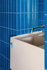 Bathroom with a white ceramic sink, silver faucet, and blue tiles on the walls and floor, creating a clean and well-maintained atmosphere