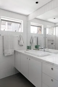 A minimalist bathroom with a white sink, mirror, and towel rack, featuring two towels and a clean design