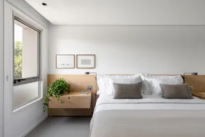 A cozy bedroom with two twin beds, potted plants, and a book, creating a relaxing atmosphere