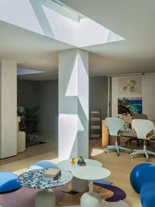 Open living area with a unique white wall design, furniture, books, and natural light