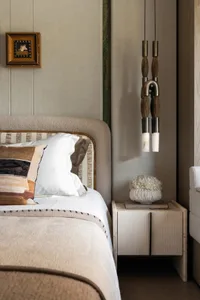 A cozy hotel bedroom with a large bed, white bedding, and wooden paneling on the walls