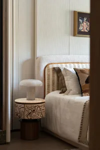 A cozy bedroom with a large white bed, wooden headboard, nightstand, and a painting above the bed