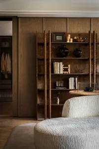 Cozy bedroom with wooden floors and walls, featuring two bookshelves and decorative vases, creating a warm and inviting atmosphere
