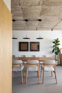 A cozy dining area with a wooden table surrounded by six chairs, a potted plant, and a warm atmosphere
