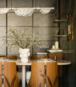 Warm and inviting dining area with a wooden table, four chairs, and a vase, surrounded by a cozy atmosphere