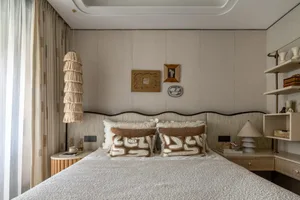 A well-lit bedroom with a large white bed, brown pillows, and a cozy atmosphere