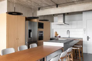 Open kitchen area with wooden floors, white walls, and various appliances, including a refrigerator, oven, and sink, with multiple bottles placed around the space, creating a clean and organized atmosphere