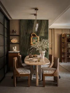 Dining area with a wooden table and chairs, surrounded by books and decorative items, creating a cozy atmosphere