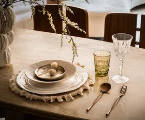 A dining table with wine glasses, cups, a bowl, and a spoon, surrounded by three chairs
