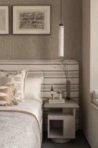 Cozy bedroom with a large bed, two lamps, and scattered books, featuring a warm and inviting atmosphere