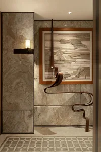 Cozy bathroom with a brown tile wall, a picture hanging on it, and two lights, creating a warm and inviting atmosphere