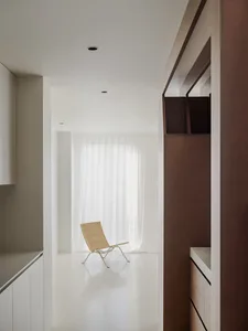 Empty white living room with a wooden floor, two chairs, and natural light from windows