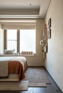 A well-lit bedroom with a bed near a window, two pillows, and a calm atmosphere