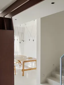 Open living space with a wooden dining table, chairs, and a modern couch, featuring clean lines and minimalistic decoration