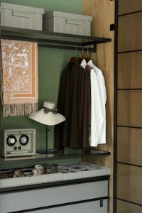 A cluttered closet with clothes, hats, scarves, and a clock, suggesting a personal storage space with disorganized contents
