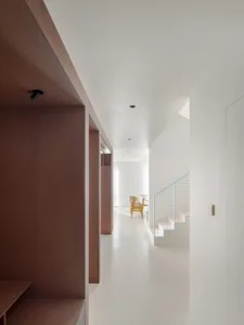Bright and inviting open concept living area with a white staircase, two chairs, and a sense of depth and perspective