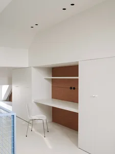 A minimalist living space with a white chair and desk, surrounded by a clean and airy atmosphere with visible stairs
