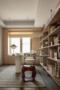 A living area with a dining table, chairs, and a couch, featuring a wooden floor and neutral-colored walls, with books on the table creating a cozy atmosphere