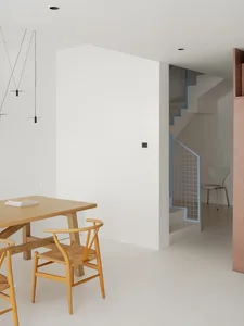 Open dining space with a white color scheme, concrete walls, and a dining table surrounded by chairs