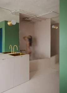 A woman takes a shower in a private bathroom with a sink and mirror, surrounded by a sense of intimacy