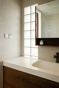 Bathroom with a white sink, mirror, and window, featuring a clean and well-lit atmosphere