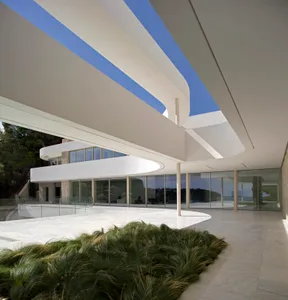 A modern building with a curved structure and a large glass wall that allows natural light to enter the interior spaces, creating a bright and airy atmosphere