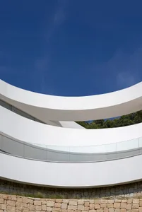 Modern building with a curved design and glass exterior, featuring a clean and minimalist aesthetic