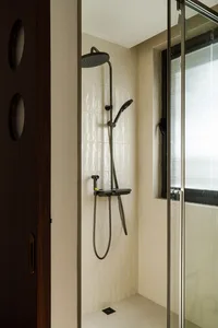 Bathroom with a tile shower, black shower head, and silver pole, featuring natural light from a window