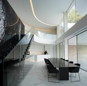 Open modern living space with a black table, two chairs, and a kitchen area with a sink, giving off a sleek and modern vibe