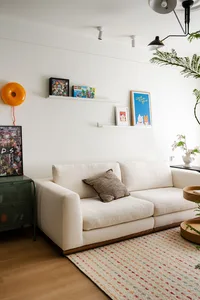 Cozy living room with a white couch on a hardwood floor, surrounded by potted plants and decorative vases
