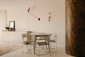 Empty living room with white walls and floors, featuring a dining table with four chairs arranged in a symmetrical layout