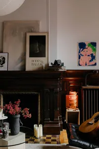 Cozy living room with a fireplace, bookshelves, vases, and potted plants, creating a warm and inviting atmosphere