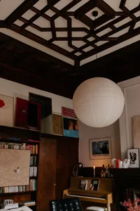 Warm and inviting living area with wooden floors and walls, featuring books, a vase, and a bottle, with a comfortable and cozy atmosphere
