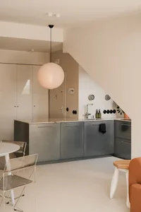 Open modern kitchen and dining space with white walls, grey cabinets, a dining table, and two chairs