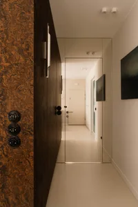 Narrow hallway with a white wall and two wooden door frames, creating a cozy and traditional atmosphere