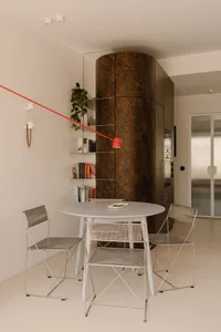 Modern dining space with a metal table, three chairs, and a potted plant, featuring clean lines and simple design elements