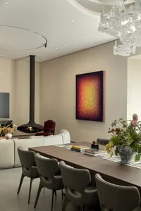 Cozy living space with a dining table, chairs, paintings, and a fireplace, with books and vases adding to the aesthetic