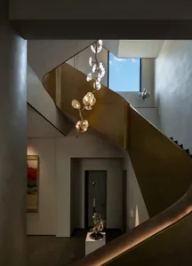 Sleek spiral staircase in a modern building with gold metal stairs, illuminated by sunlight through a window, creating a warm and inviting atmosphere