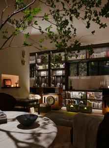 Cozy home study with a bookshelf, dining table, and vases, featuring warm and inviting atmosphere with wooden furniture