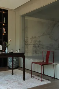 Cozy living space with a red chair, books, vases, and a table, inviting relaxation and leisure activities