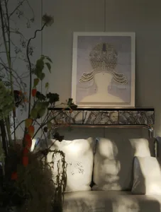 A sophisticated living area with a white couch, a chair, and a painting on display, set against a stone wall