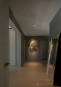 A modern hallway with a large mirror, a painting, and wooden surfaces, featuring two doors and clean lines