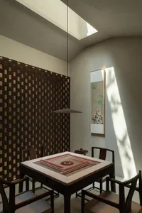 A cozy dining area with a red tablecloth, three chairs, and a vase on a table, creating a warm and inviting atmosphere
