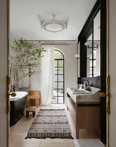 Luxurious bathroom with a white bathtub, two sinks, and a large window for natural light