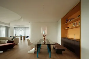 Open modern living space with a dining table, chairs, a couch, and a vase, well-lit and inviting